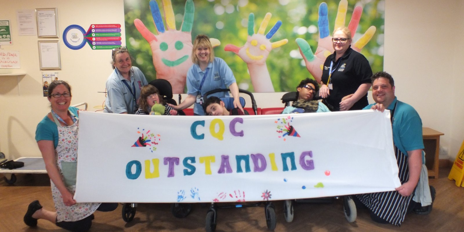 Naomi House and Jacksplace care team and children holding CQC Outstanding banner