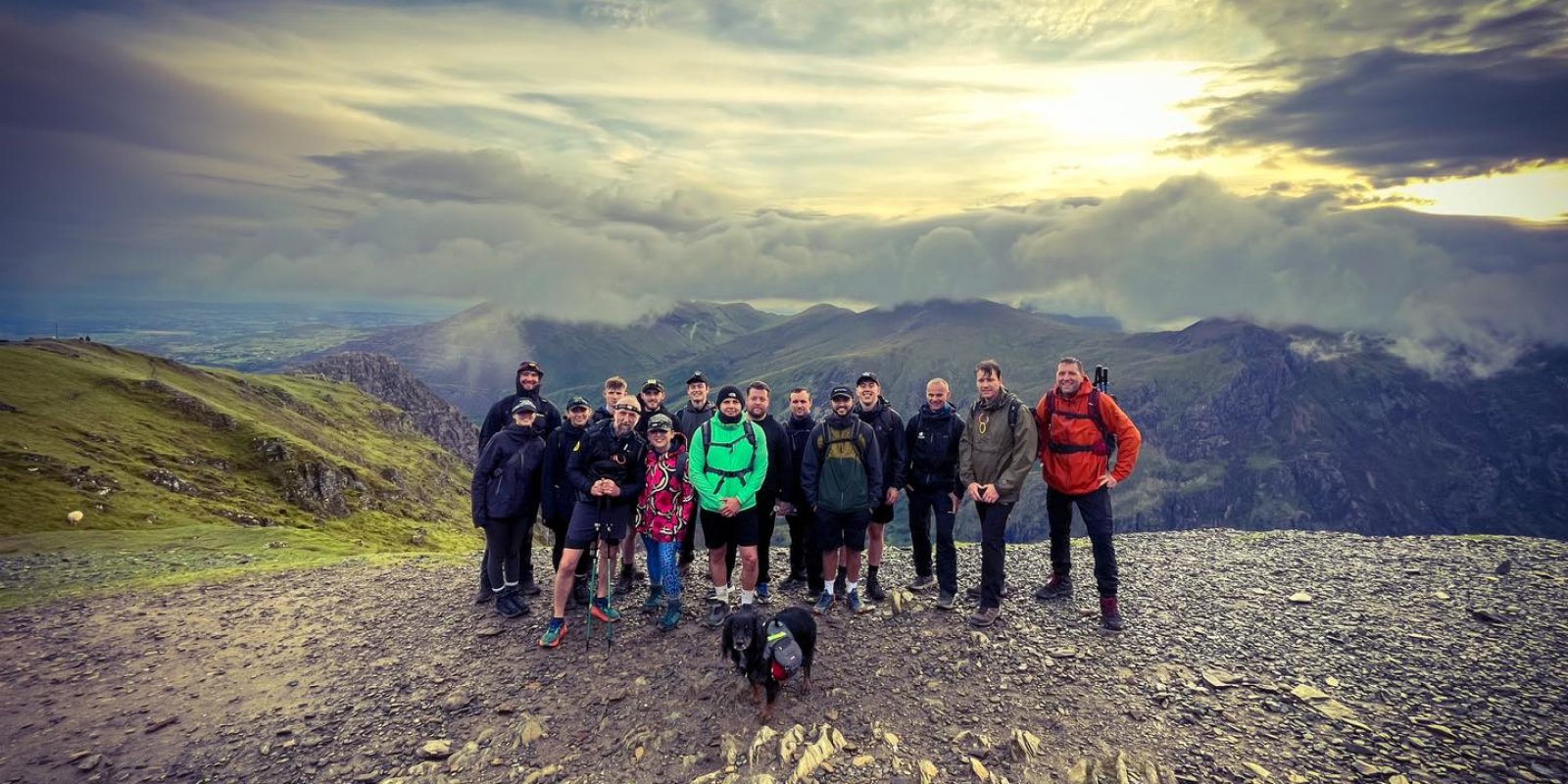 a group of people standing at the top of a mountain with sunlight